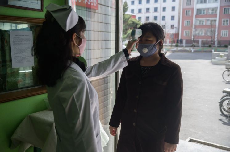 북한 평양의 평천구역병원 입구에서 1일 간호사가 신종 코로나바이러스 감염증(코로나19) 확산을 막기 위해 방문자의 체온을 재고 있다.  <사진=AFP연합>