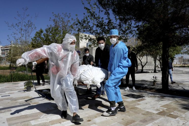 방호복을 입은 이란 의료진이 30일(현지시간) 테헤란 외곽 공동묘지에서 신종 코로나바이러스 감염증(코로나19) 사망자의 시신을 옮기고 있다. <사진=AP연합>