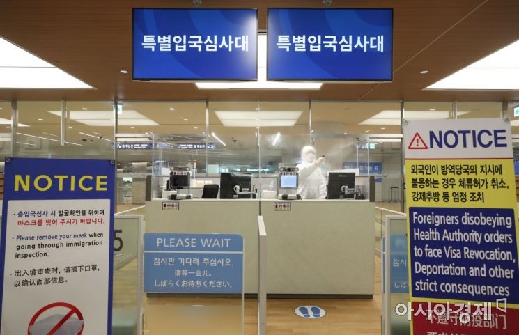 법무부 인천공항 출입국 외국인청 입국심사관이 8일 인천국제공항 2터미널 유증상자 전용 입국 심사대에서 유럽발 입국자들을 기다리던 중 자리를 소독하고 있다. /문호남 기자 munonam@
