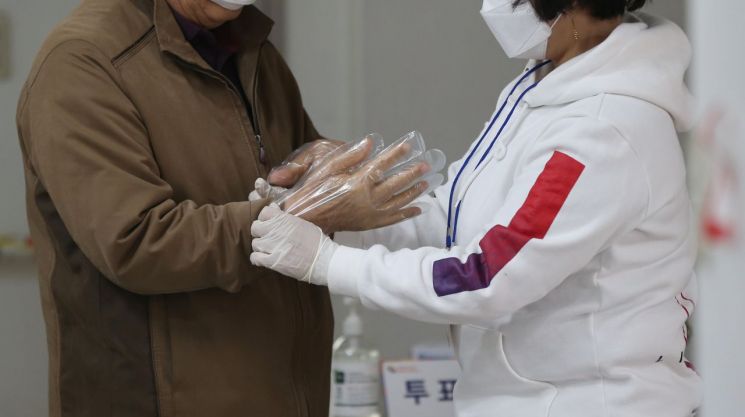 제21대 국회의원선거 사전투표 첫날인 지난 10일 오전 울산시 남구 울산보훈지청에 마련된 옥동 사전투표소에서 선거사무원이 유권자 손에 비닐장갑을 끼워 주고 있다/사진=연합뉴스
