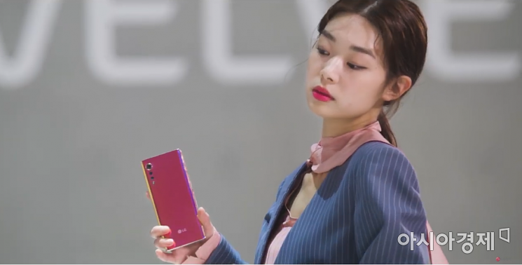 LG 벨벳 온라인 런칭쇼에서 한 여성 모델이 LG 벨벳을 일루전 선셋 모델을 들고 포즈를 취하고 있다.(출처=LG전자 유튜브)
