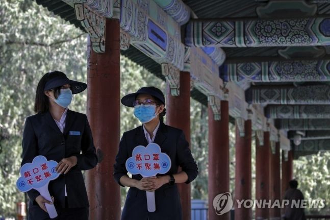 중국 베이징 한 사원에서 '마스크를 착용하고 모임을 금지한다'는 팻말을 든 직원 / 사진=연합뉴스