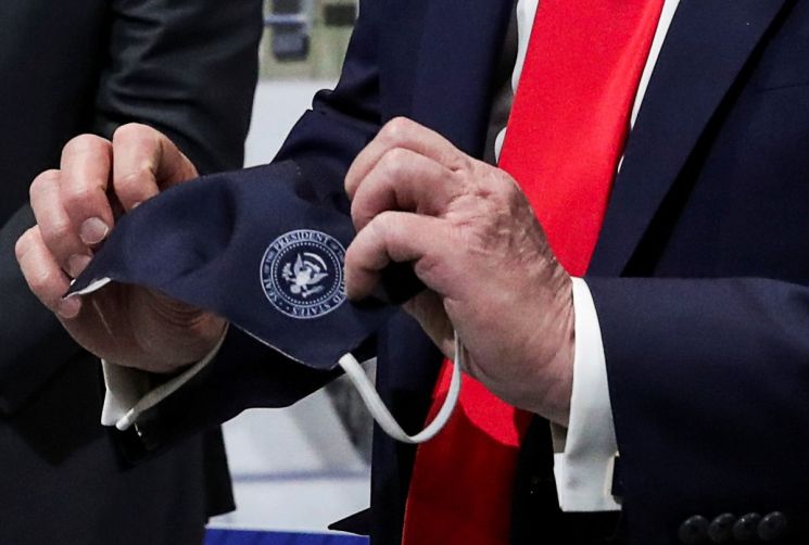 도널드 트럼프 미국 대통령이 21일(현지시간) 미시간 주 입실랜티에 있는 포드 자동차 공장 방문 중 대통령 직인이 찍힌 마스크를 손에 들고 있다. 트럼프 대통령이 마스크를 착용한 모습은 이날 미국 언론에 처음으로 포착됐다. [이미지출처=연합뉴스]