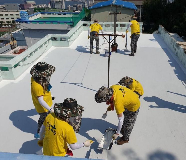 지난해 '하얀지붕' 사업에 나선 재능기부 봉사자들이 지붕 옥상을 흰색 페인트로 시공하고 있다.