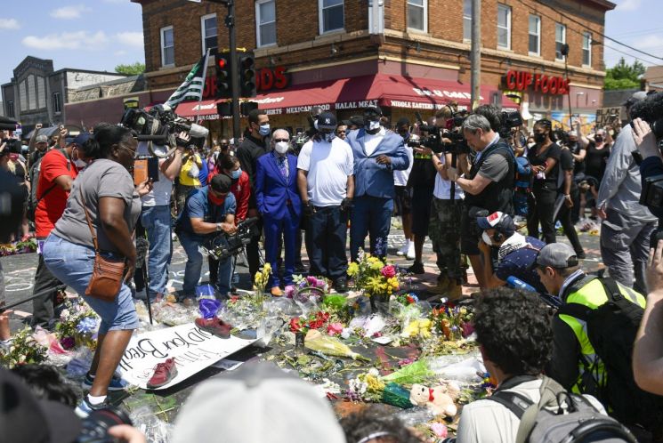 1일(현지시간) 검은색 모자와 힌 티셔츠를 입은 조지 플로이드의 동생이 형이 사망한 장소에 놓인 꽃을 바라보고 있다. [이미지출처=EPA연합뉴스]