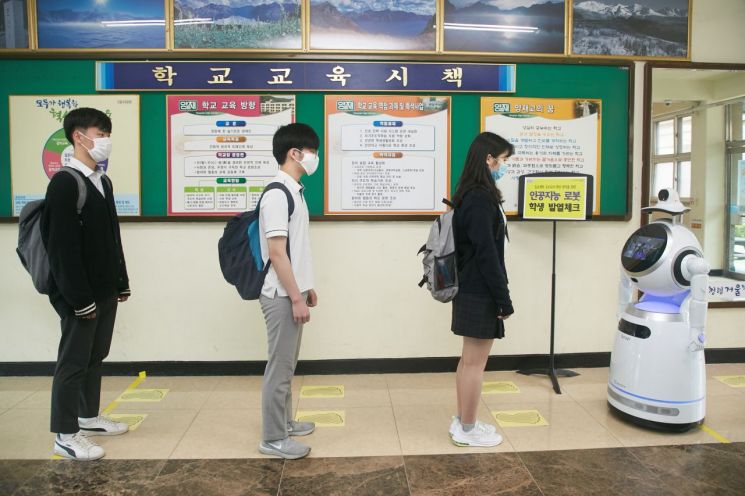 양재고등학교 학생들이 일정거리를 두고 AI 로봇을 통해 체온을 체크중이다.