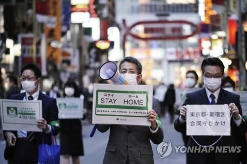 지난 4월24일 도쿄의 대표적 유흥가인 신주쿠구 가부키초 거리에서 마스크를 쓴 도쿄도 직원들이 시민들에게 외출 자제를 당부하고 있다. / 사진=연합뉴스
