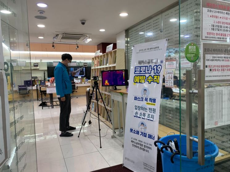 9일 오후 서울 동작구 노량진에 위치한 한 공무원 시험 학원. 출입구에 설치된 열화상 카메라로 학원 관계자가 출입자들의 체온을 점검하고 있다./사진=김슬기 인턴 기자 sabiduriakim@asiae.co.kr