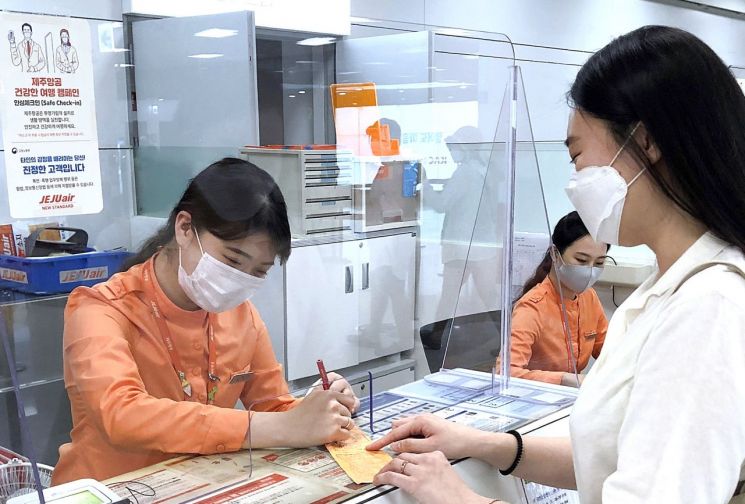 제주항공 직원이 6월13일 제주국제공항의 기존 발권 카운터에 투명 가림막을 설치한 '안심 체크인' 카운터에서 고객을 응대하고 있다. [이미지출처=연합뉴스]