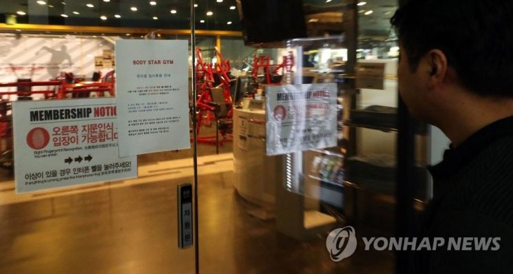 지난 3월23일 서울 동대문구 한 헬스장 출입구에서 이용객이 출입문에 부착된 정부 정책에 따라 휴업한다는 안내 문구를 살펴보고 있다.사진은 기사 내용과 관련 없음 [이미지출처=연합뉴스]