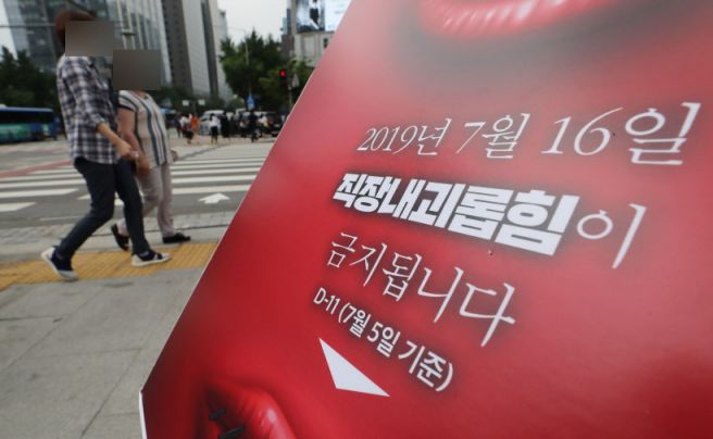 '직장 내 괴롭힘 금지법'이 시행된 지난해 7월16일 서울 광화문광장에서 직장갑질119 관계자들이 설치한 관련 안내판 뒤로 시민들이 지나가고 있다.사진=연합뉴스