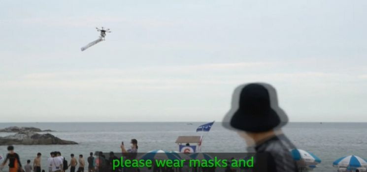코로나19 안전수칙 안내문을 달고 해수욕장 상공을 날고 있는 드론의 모습. 사진=BBC방송 캡처.