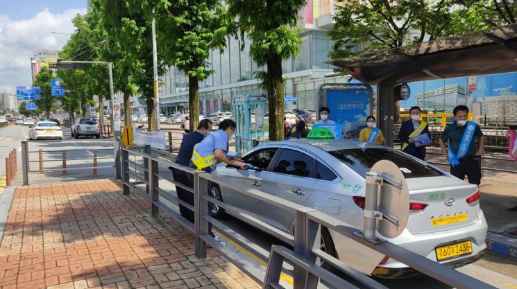 광주광역시 대중교통과 공무원과 버스·택시운송사업조합, 교통문화연수원 관계자들이 광주종합버스터미널과 광주송정역 택시 승강장에서 ‘대중교통 이용 시 마스크 착용의무’ 캠페인을 펼치며 정차한 택시에 홍보 스티커를 부착하고 시민들에게 마스크를 나눠주고 있다. 사진=광주광역시 제공