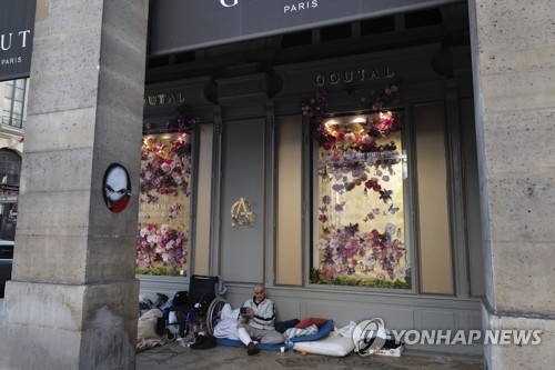 프랑스에 봉쇄령이 내려진 지난 4월 파리 한 고급품 상점 앞에서 노숙자가 쉬고 있다. / 사진=연합뉴스