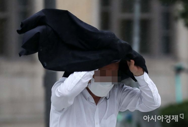 제8호 태풍 '바비'의 영향으로 비가 내린 27일 서울 광화문 사거리에서 한 시민이 외투로 비를 피하고 있다. /문호남 기자 munonam@