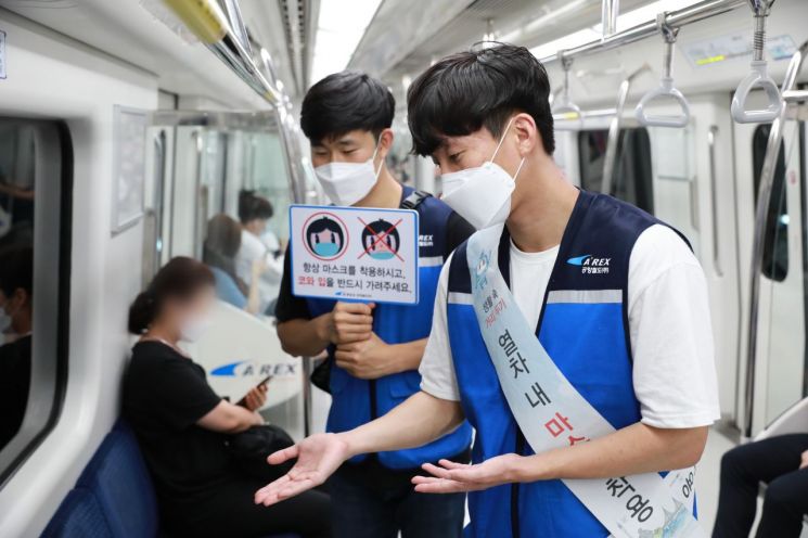 공항철도 일반열차 내에서 계도요원들이 승객에게 마스크 착용을 권하고 있다. [사진=공항철도]