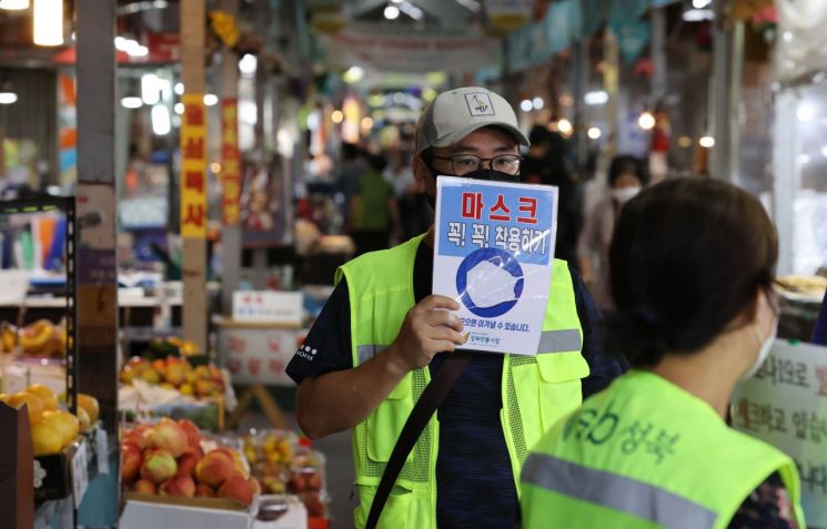 2일 서울 성북구 사랑제일교회 인근 장위전통시장 입구에서 성북구청 관계자가 마스크 착용 팻말을 들어보이고 있다.[이미지출처=연합뉴스]
