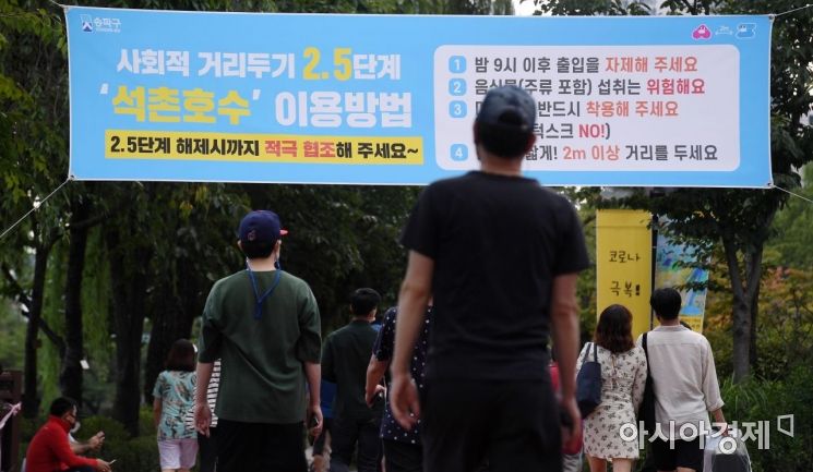 코로나19 재확산으로 강화했던 사회적 거리두기가 2단계로 하향 조정된다. 사진은 13일 서울 송파구 석촌호수에서 마스크를 착용하고 산책하는 시민들의 모습./김현민 기자 kimhyun81@