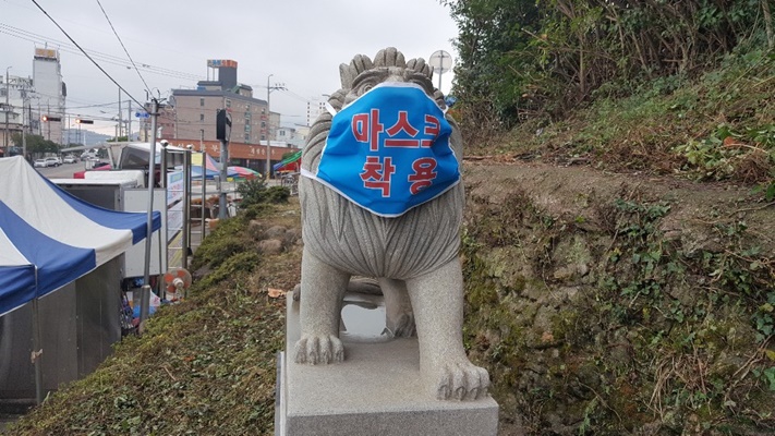 완도전통 시장 입구애 이용객들에게 마스크 착용을 당부하고자 사자상에 마스크를 씌웠다. (사진=완도군 제공)