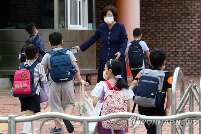 한 초등학교에서 교장 선생님이 학생을 맞이하고 있다. 사진=연합뉴스