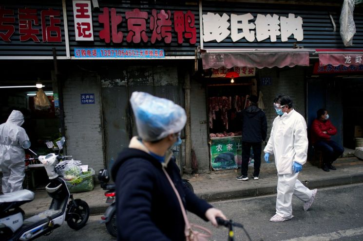 지난 4월 중국 우한의 한 시장에서 방호복을 입은 사람들이 지나다니고 있다. [이미지출처=로이터연합뉴스]