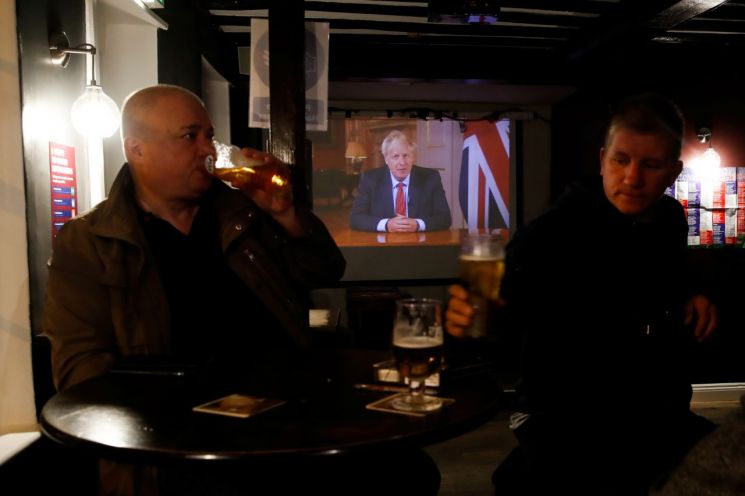 22일(현지시간) 영국의 한 펍에 설치된 TV에서 대국민 연설을 하고 있는 보리스 존슨 총리의 모습이 보이고 있다. [이미지출처=로이터연합뉴스]
