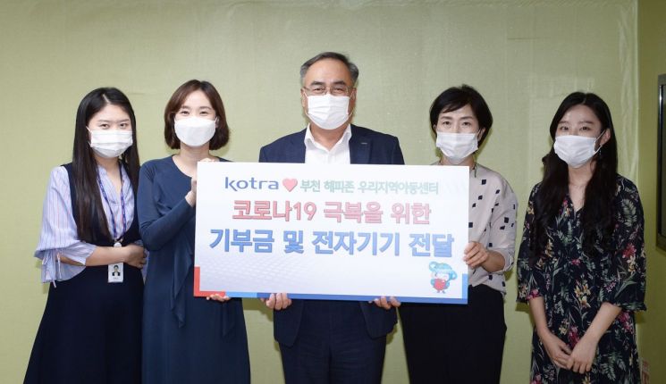 KOTRA가 25일 부천 ‘해피존 지역아동센터’를 찾아 교육용 전자기기와 임직원 기부금을 전달했다. 김종춘 KOTRA 부사장(가운데) 등 참석자들이 기부식에서 기념촬영을 하고 있다.