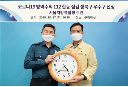 성북구가 서울지방경찰청 주관 「코로나 방역수칙 위반 112신고 및 지자체-경찰 간 공동대응」 실적 우수 자치구로 선정됐다. 이에 따라 서울지방경찰청장 명의의 벽시계가 전달되어 지난 27일 최성규 성북경찰서장(왼쪽 첫 번째)와 이승로 성북구청장(오른쪽 첫 번째)이 간담회를 진행하고 기념사진을 촬영하고 있다.