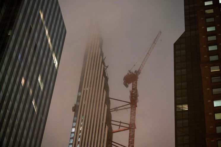 짙은 구름을 뚫고 서있는 건물의 타워크레인이 바람에 흔들리고 있다. [이미지출처=로이터연합뉴스]
