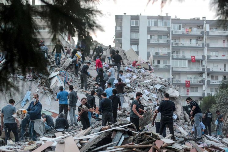 터키 서부 이즈미르의 한 건물이 강진으로 무너져 주민들이 잔해를 치우고 있다.(사진=연합뉴스/AFP)