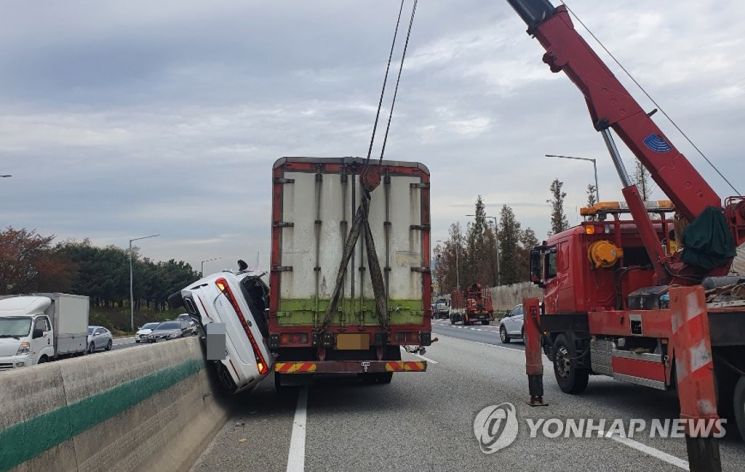 화물차와 중앙분리대 사이에 끼여버린 승용차. [이미지출처=연합뉴스]