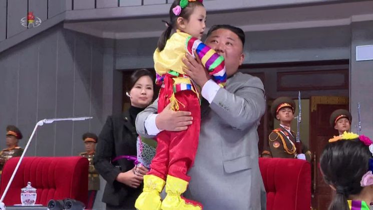 김정은 북한 국무위원장이 11일 평양 5월1일 경기장에서 노동당 창건 75주년을 기념하는 대집단체조와 예술공연 '위대한 향도'를 관람했다고 조선중앙TV가 지난달 12일 보도했다. 꽃다발을 건네받은 김정은 위원장이 화동을 번쩍 들어 안고 있다. 현송월 선전선동부 부부장이 김 위원장의 옆에서 의전을 맡고 있다.