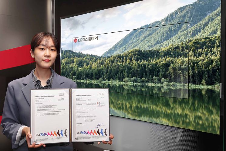 LG디스플레이 직원이 OLED TV 앞에서  스위스 검사, 인증기관인 SGS 인증서를 들고 기념 사진을 촬영하고 있다.