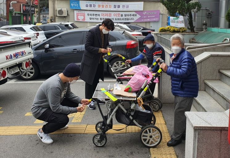 동대문구 장안1동 주민센터 직원들이 폐지수집 어르신 손수레에 반사테이프를 부착해주고 있다.