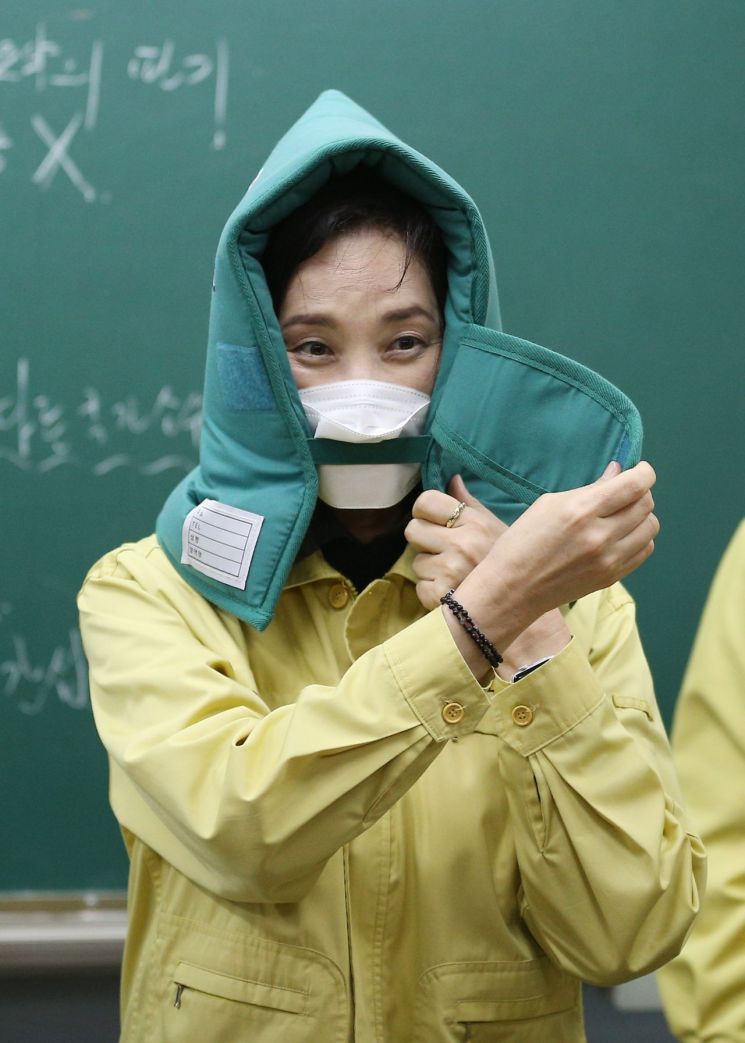 유은혜 부총리 겸 교육부 장관이 19일 대학수학능력시험(수능) 준비 상황을 점검하기 위해 경북 경주시 경주여자고등학교를 방문, 2학년 교실을 찾아 지진 발생 때 머리 보호를 위한 방재 두건을 착용해보고 있다. [이미지출처=연합뉴스]