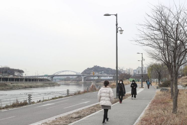 청계천변 음악방송을 위한 스피커가 설치된    산책로를 주민들이 걷고 있다.