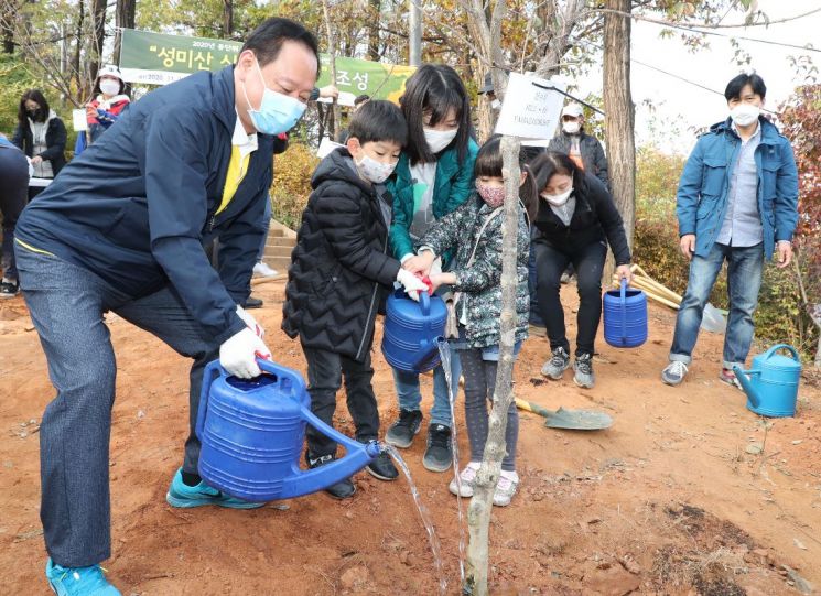 유동균 마포구청장이 지난달 나무시기 행사에 참석, 나무를 심은 후 물을 주고 있다.