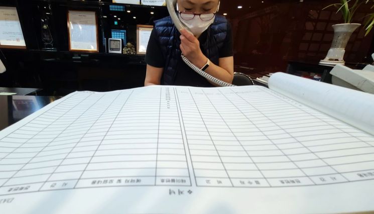 22일 서울 종로구 한 음식점에서 관계자가 연말 모임과 관련한 예약 취소 전화 통화를 하고 있다. 식당 관계자는 평년 연말에는 손님이 몰려 예약 장부에 종이를 덧붙여가며 예약을 받았지만, 올해는 예약한 손님마저 취소 문의를 한다고 전했다. [이미지출처=연합뉴스]