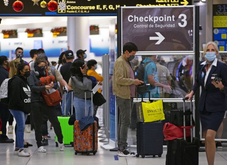 28일(현지시간) 미국 플로리다주 마이애미 국제공항에서 마스크를 쓴 여행객들이 보안검색대를 통과하기 위해 줄을 서 있다. 미국 내 여행객 숫자는 27일 하루에만 130만여명으로 지난 3월 이후 가장 높은 수치를 기록했다. 신종 코로나바이러스감염증(코로나19) 확산을 막기 위해 미국 정부는 여행을 자제해달라고 권고했지만 여행객들을 막기엔 역부족인 상황이다. 마이애미(미국)=AP·연합 [이미지출처=AP연합뉴스]