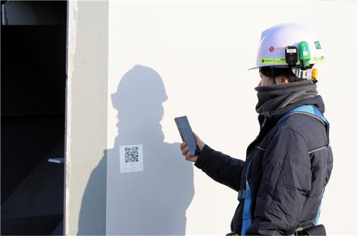 A Lotte Construction official is scanning the QR code of materials brought to the site using the 'Elloseum' application. Elloseum is a smart construction site management platform developed in-house by Lotte Construction and is applied to various construction sites such as the Geumgang Pedestrian Bridge.