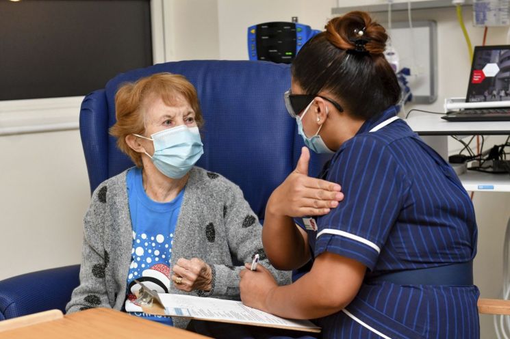 지난해 12월 세계 최초의 코로나19 백신 일반 접종자인 마가렛 키넌(90) 할머니 화이자 백신을 접종받기 전 간호사의 설명을 듣고 있다. [이미지출처=AP연합뉴스]