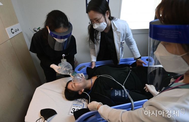 9일 오후 서울 중구 국립중앙의료원 종합암예방접종센터에서 열린 백신 접종 모의 훈련에서 의료진들이 접종을 마친후 이상반응을 보인 참자자를 응급처치하고 있다./사진공동취재단