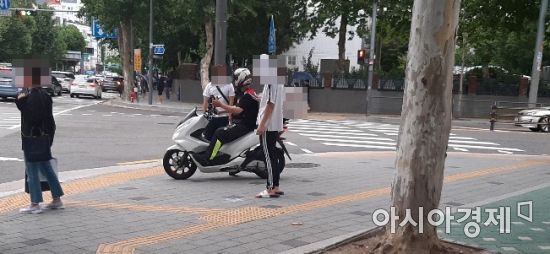 한 배달용 오토바이가 인도에 올라와 횡단보도 신호를 대기하고 있다. 오토바이 주변으로 통행을 하고 있는 시민들이 보인다. 사진=한승곤 기자 hsg@asiae.co.kr