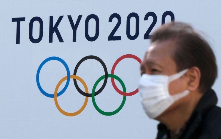 지난 2월4일 마스크를 쓴 한 행인이 도쿄에서 올림픽 로고 앞을 지나가는 모습. [이미지출처=연합뉴스]