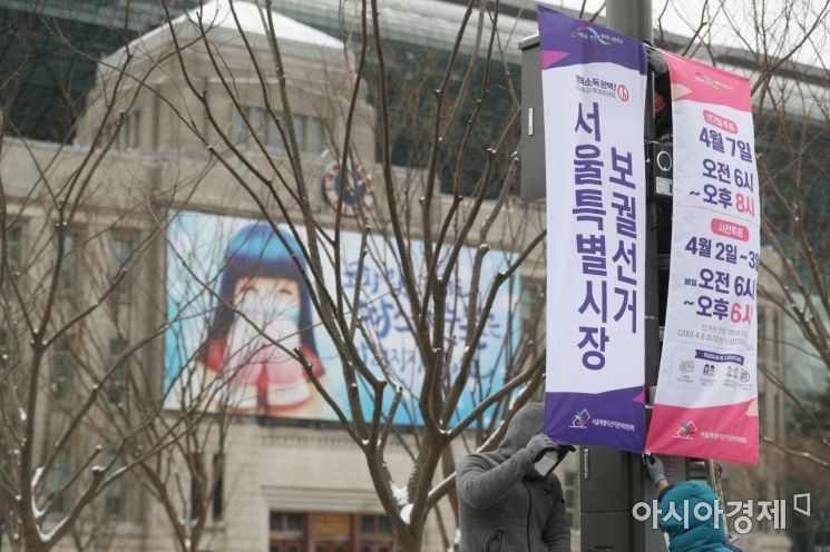 서울·부산 시장 보궐선거가 50일 앞으로 다가온 16일 서울시선거관리위원회 관계자들이 시청 인근 도로변에서 선거일을 알리고 유권자의 투표 참여를 독려하기 위해 가로등 현수기를 설치하고 있다. /문호남 기자 munonam@