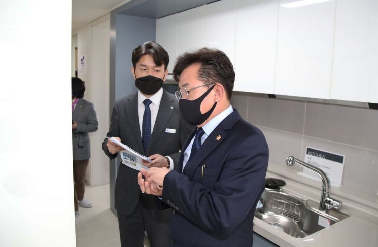 박근철 더불어민주당 대표의원(오른쪽)이 기본주택 홍보관 관계자로부터 설명을 듣고 있다.