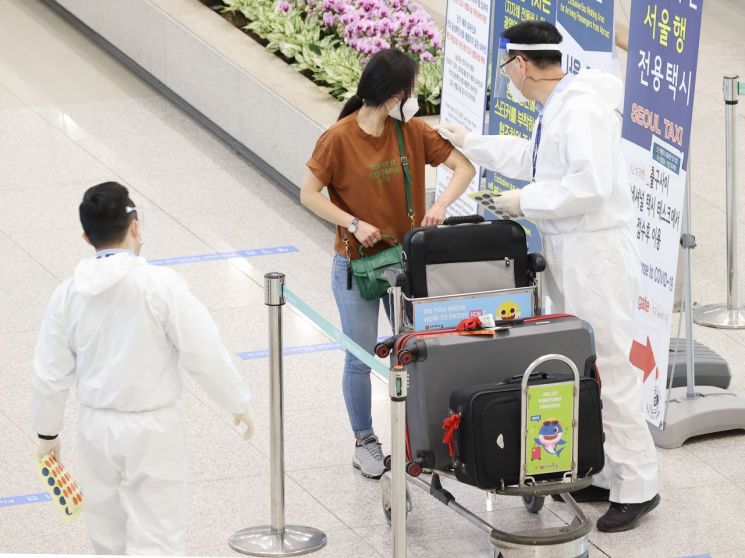 21일 인천국제공항 제1여객터미널 입국장에서 방역관계자가 입국객 어깨에 식별 스티커를 붙이고 있다. [이미지출처=연합뉴스]