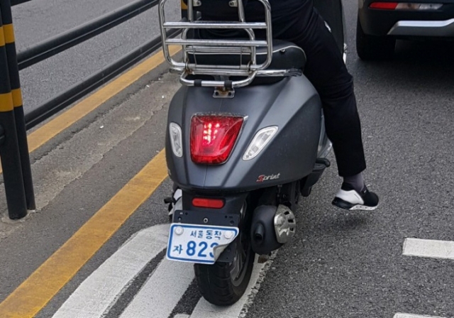 교통 법규 위반 단속·신고를 회피하기 위해 오토바이의 번호판을 접어 놓은 한 배달 라이더의 모습. /사진=온라인 커뮤니티 갈무리