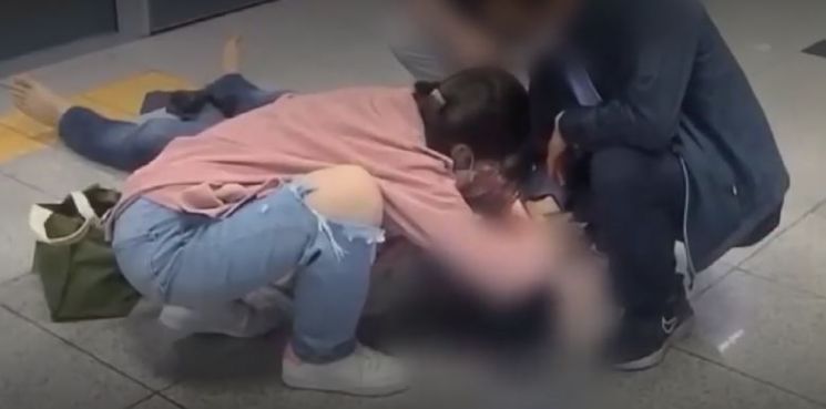 지난 11일 서울 지하철 9호선 승강장에 의식을 잃고 쓰러진 남성을 발견한 간호사 권영선씨가 스마트폰 불빛을 이용해 남성의 동공 상태를 확인하고 있다. [사진제공=채널A]