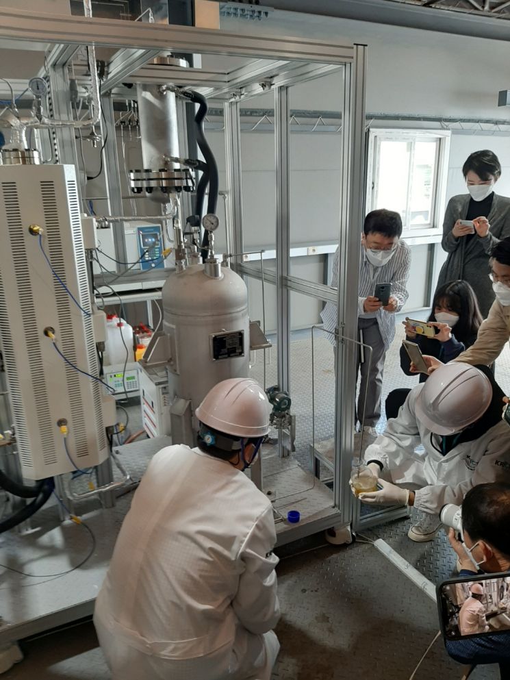 25일 한국화학연구원 관계자들이 이산화탄소를 전환해 만든 나프타를 병에 따라 보이고 있다.